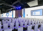 all white room setup for corporate meeting with projection screens.