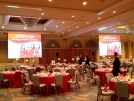 Ballroom set for lunch with two large screens displaying images.