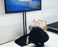 technician placing cover on TV display stand setup for corporate meeting.